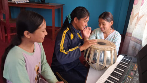 3 Mädchen spielen die Trommel und lachen.